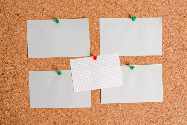 Corkboard with different color and size papers fixed by a pin. Rectangle and square shaped sheets stuck on a billboard by colored thumbtacks. Notice board with empty reminder note. - Photo, Image