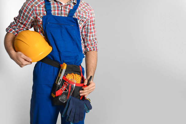 Construction worker with tool belt on light background, closeup. Space for text - Φωτογραφία, εικόνα