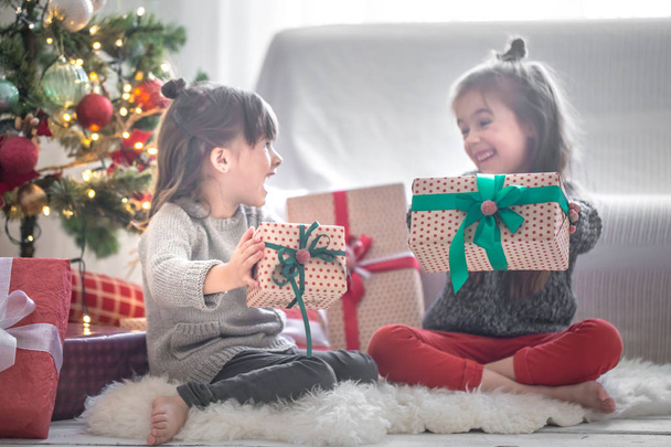 Τα όμορφα κοριτσάκια κρατούν κουτιά δώρων και χαμογελούν στο σπίτι. - Φωτογραφία, εικόνα