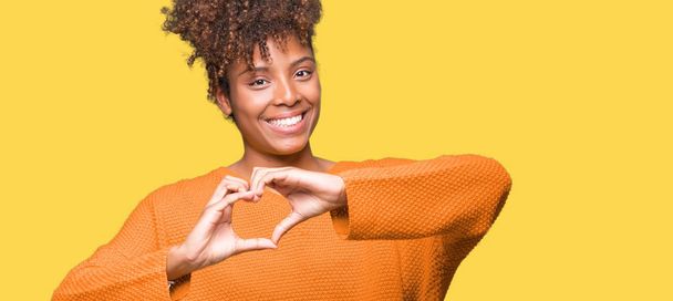 Mooie jonge Afro-Amerikaanse vrouw op geïsoleerde achtergrond glimlachend in liefde met hartsymbool en vorm met de handen. Romantische concept. - Foto, afbeelding