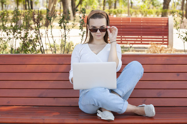 Young girl on a bench with a laptop. - Foto, imagen