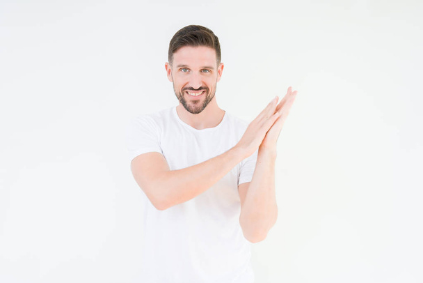 Young handsome man wearing casual white t-shirt over isolated background Clapping and applauding happy and joyful, smiling proud hands together - Photo, image