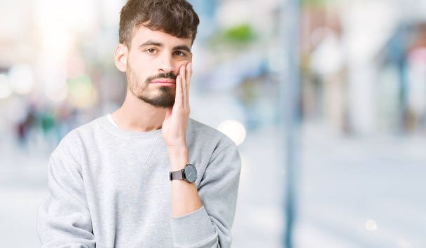 Young handsome man wearing sweatshirt over isolated background thinking looking tired and bored with depression problems with crossed arms. - Photo, Image