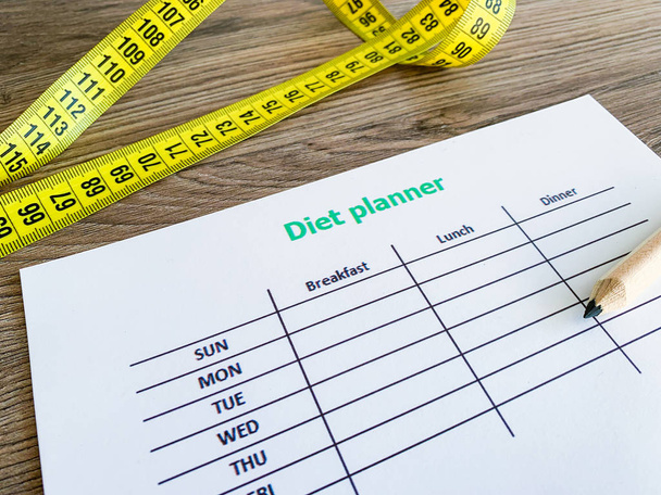 Концепция диеты. Измерение ленты и плана диеты на деревянном фоне
 - Фото, изображение