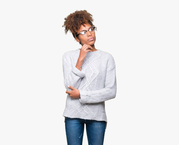 Piękna młoda kobieta african american swetrze zima nad na białym tle ręką na podbródek myślenia o pytanie, wyrażenie zamyślony. Uśmiech z twarzy przemyślane. Koncepcja wątpliwości. - Zdjęcie, obraz