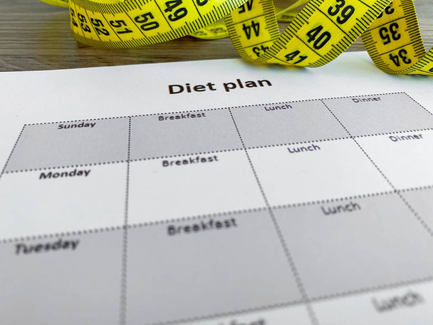 Dieet plan concept. Meetlint en dieet plan op houten achtergrond - Foto, afbeelding