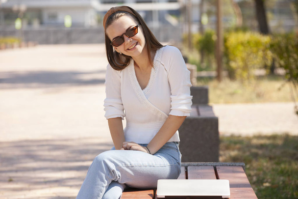 Beautiful woman sitting on a park bench using a laptop. - Foto, Imagen