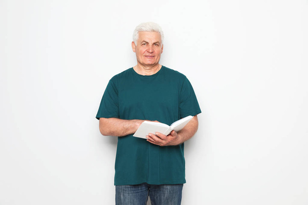Senior man reading book on white background - Photo, Image