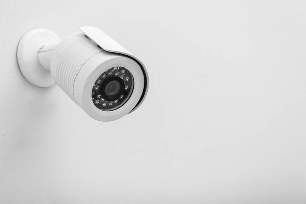 Modern CCTV security camera on white wall. Space for text - Photo, Image