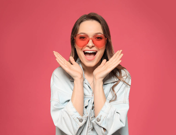 Portrait of emotional young woman with heart shaped sunglasses on color background - Φωτογραφία, εικόνα