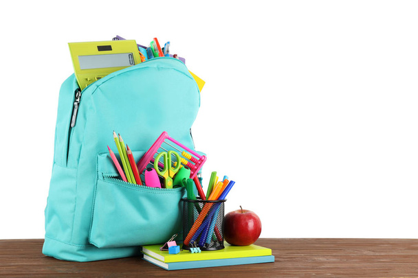 Bright backpack with school stationery on brown wooden table against white background, space for text - Fotografie, Obrázek