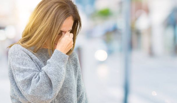 Όμορφη μέσης ηλικίας γυναίκα που φοράει χειμώνα πουλόβερ πάνω από απομονωμένες φόντο κουρασμένος τρίβοντας τη μύτη και τα μάτια, αίσθημα κόπωσης και πονοκέφαλο. Άγχος και την απογοήτευση έννοια. - Φωτογραφία, εικόνα