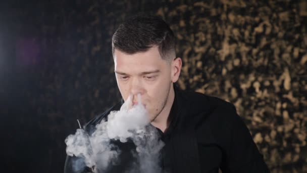 Yakışıklı genç beyaz adam nargile sigara ve karanlık odada duman yüzük yapma portresi. Sihirli sanat sis, kötü habbits. Acımasız adam nargile barda rahatlatıcı. Yavaş hareket. Hd - Video, Çekim