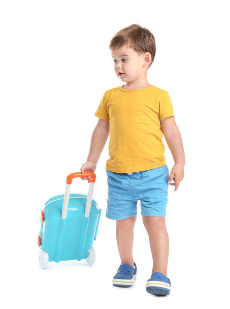 Cute little boy walking with blue suitcase on white background - Photo, image