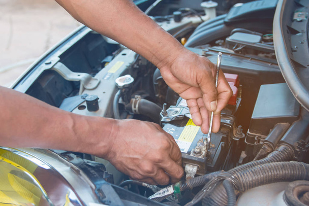 Mechanik samochodowy Zainstaluj baterię z kluczem w garażu. Repa. - Zdjęcie, obraz