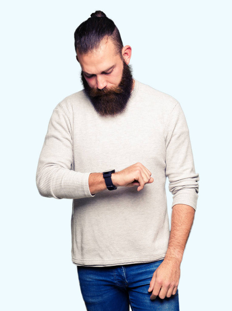Joven hombre rubio con suéter casual Comprobación de la hora en el reloj de pulsera, relajado y seguro
 - Foto, imagen