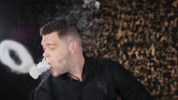 Portret van knappe jonge Kaukasische kerel roken waterpijp en het maken van ringen van rook in donkere kamer. Magische kunst mist, slechte habbits. Brutale man ontspannen in waterpijp bar. Slow Motion. Hd - Video