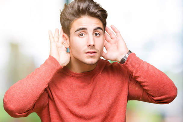 Young handsome man over isolated background Trying to hear both hands on ear gesture, curious for gossip. Hearing problem, deaf - Fotoğraf, Görsel
