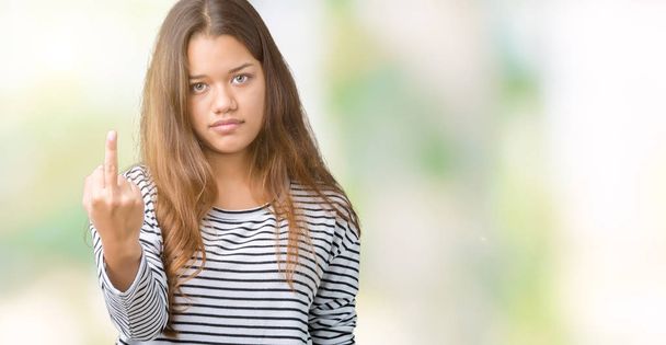 junge schöne brünette Frau trägt Streifen Pullover über isoliertem Hintergrund zeigt Mittelfinger, unhöflich und unhöflich fuck off Ausdruck - Foto, Bild