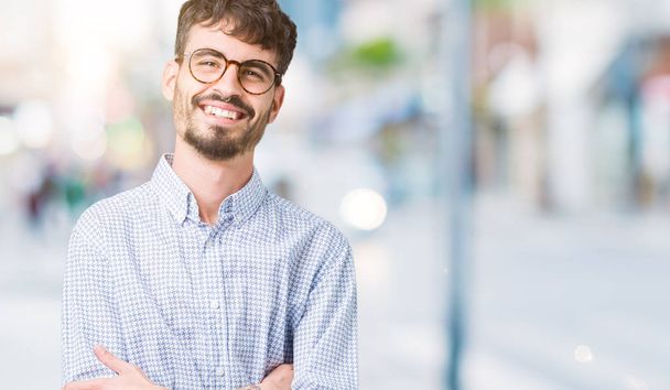 Mladý pohledný muž nosí brýle nad, samostatný pozadí šťastný obličej s úsměvem překřížené paže při pohledu na fotoaparát. Pozitivní člověk. - Fotografie, Obrázek