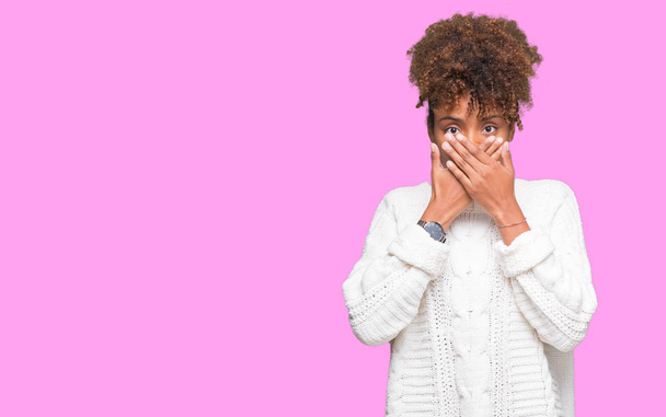 Красива молода жінка афроамериканець, носити светр на зиму над ізольованих фон шоковані прикриття рота руками за помилку. Секретний концепції. - Фото, зображення