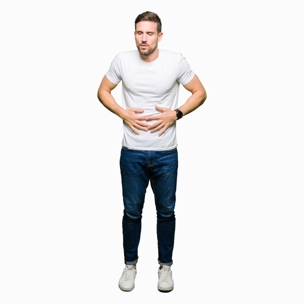 Komea mies päällään rento valkoinen t-paita käsi vatsassa, koska ruoansulatushäiriöt, kivulias sairaus huonovointisuus. Ache-käsite
. - Valokuva, kuva