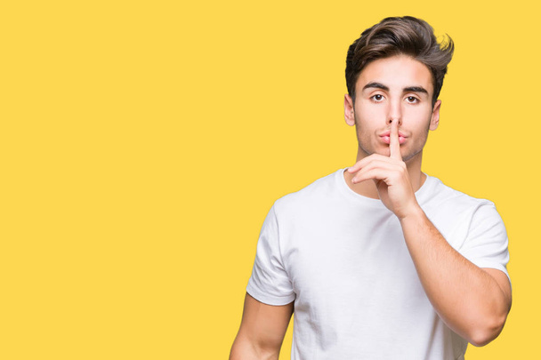 Young handsome man wearing white t-shirt over isolated background asking to be quiet with finger on lips. Silence and secret concept. - Photo, Image
