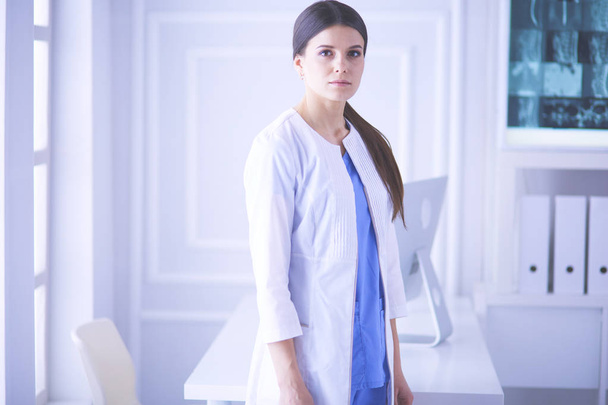 Portrait of young woman doctor in white coat standing in hospital - Photo, Image