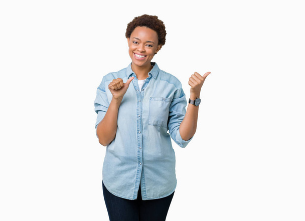 junge schöne afrikanisch-amerikanische Frau über isoliertem Hintergrund zeigt nach hinten mit der Hand und Daumen nach oben, lächelt selbstbewusst - Foto, Bild