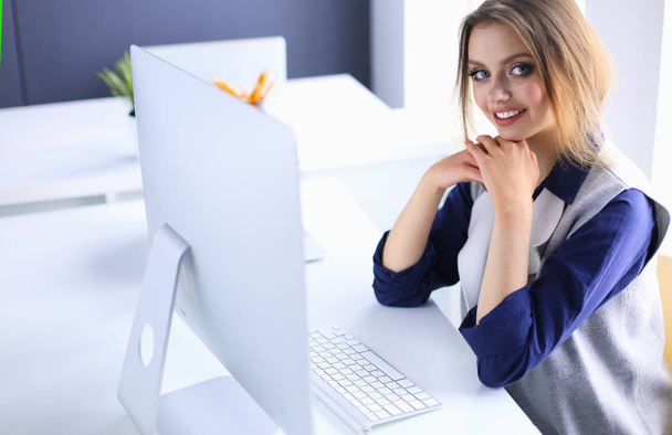 Young confident businesswoman working at office desk and typing with a laptop - Foto, Bild