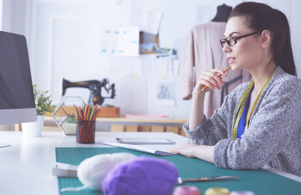 Fashion designers working in studio sitting on the desk. - Photo, image