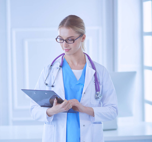 Smiling female doctor with a folder in uniform standing - Photo, image