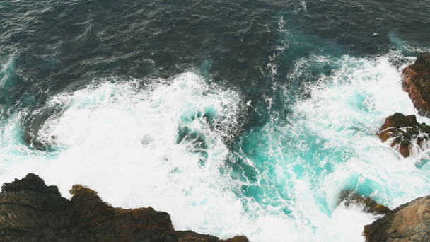 Luchtfoto van de golven van de Oceaan en de prachtige rotsachtige kust van het eiland Tenerife. Gevaarlijke golven crash tegen grote rotsen die voortkomen uit lava die de oceaan heeft bereikt en bevroren - Video