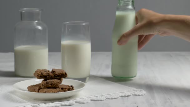 Hand puts on the wooden table a glass of milk. - Footage, Video
