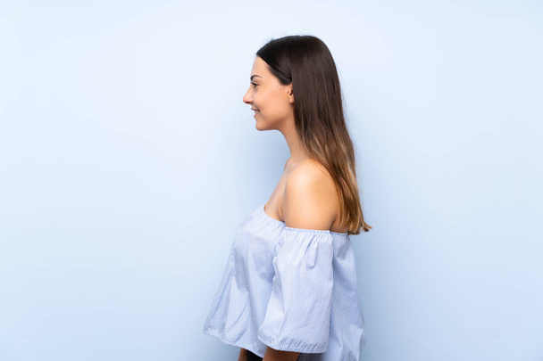 Young brunette woman over isolated blue background looking to the side - Photo, Image
