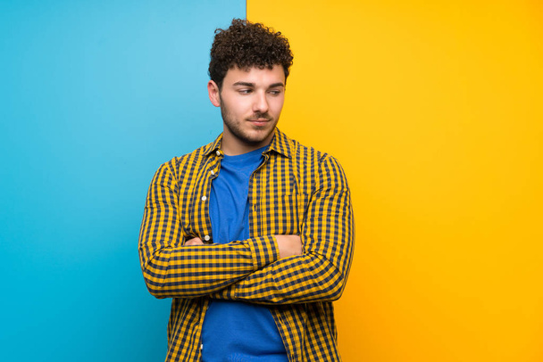Man with curly hair over colorful wall standing and thinking an idea - Foto, Imagen