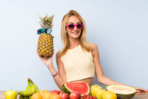 Young blonde woman holding a pineapple with sunglasses - Foto, Imagem