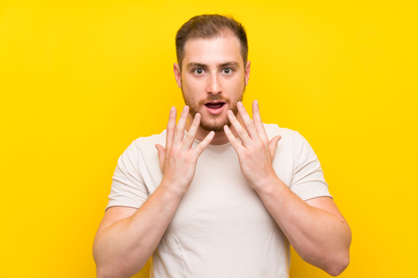 Handsome man over yellow background with surprise facial expression - Photo, Image