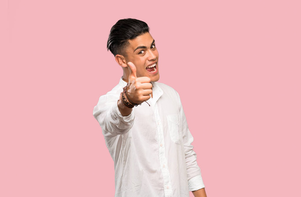 Young man with thumbs up because something good has happened on colorful background - Photo, Image