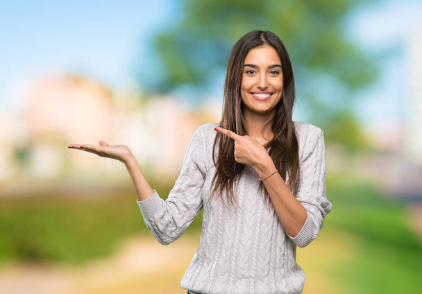 Молода іспаномовна брюнетка, що тримає копійку уявну на долоні, щоб вставити рекламу на відкритому повітрі
 - Фото, зображення