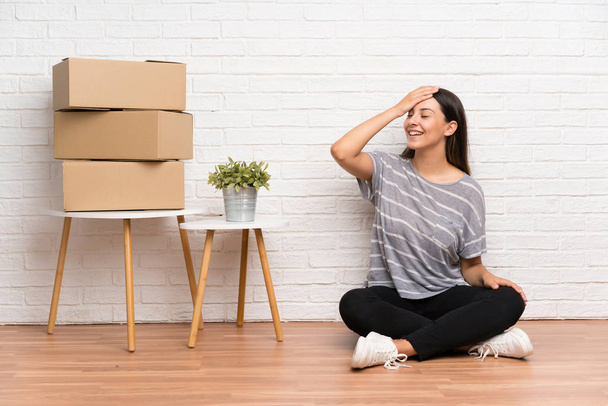 Young woman moving in new home among boxes laughing - Photo, Image