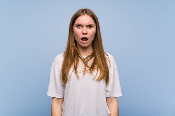 Jeune femme sur le mur bleu avec une expression faciale surprise et choquée
 - Photo, image