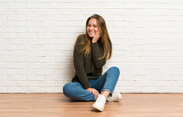 Young woman sitting on the floor smiling a lot - Φωτογραφία, εικόνα