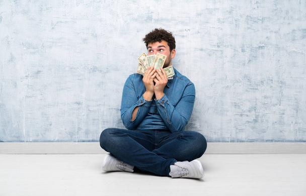 Jeune homme assis sur le sol prenant beaucoup d'argent
 - Photo, image
