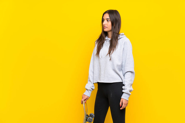 孤立した黄色の背景の上に若いスケーターの女性 - 写真・画像