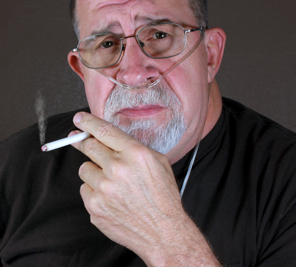 Взрослый человек курит во время ношения канюли с кислородом
 - Фото, изображение