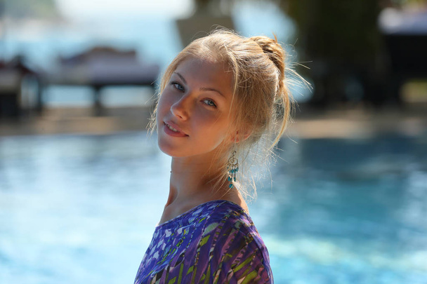 Beauty blond woman sitting on pool side at daytime - Φωτογραφία, εικόνα
