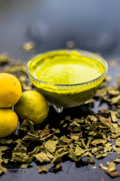 Indian Lilac face mask consisting of neem leaves paste and lemon juice well mixed with rose water for oily skin in glass on dark surface  - Фото, зображення