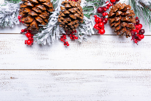 Christmas decorations on a white wood background with copy space. Pine cones, garland, berries and pine branches - Valokuva, kuva