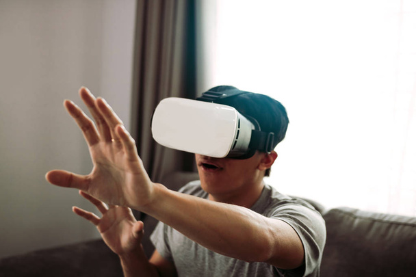 Joven asiático hombre usando virtual realidad gafas en sala de estar f
 - Foto, Imagen